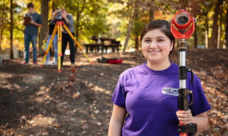 Young female student with surveying equipment